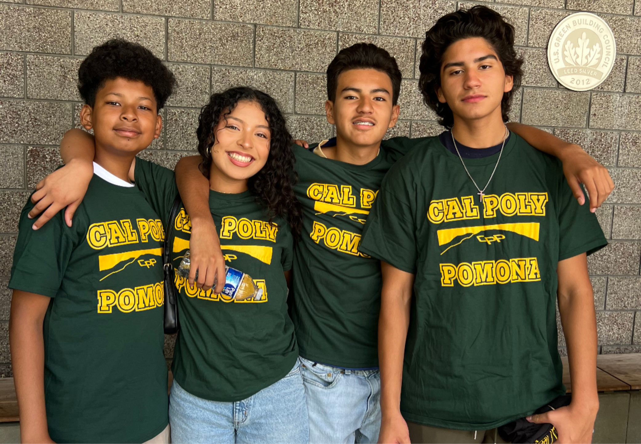 Group of four students wearing CPP shirts pose together
